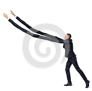A businessman on white background in side view with extremely long arms trying to grab something above.