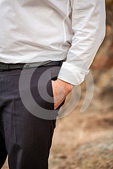 Businessman in a white shirt holding hands in his pockets. A businessman is standing with his hand in his pocket. Business concept