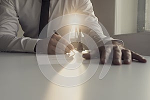 Businessman in white shirt signing document backlit by a shaft o