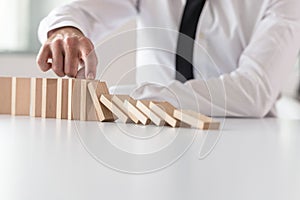 Businessman in white shirt stopping domino effect