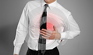 Businessman in a white shirt and tie holding his chest. Pain in photo