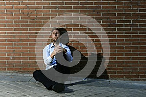 Businessman who lost job lost in depression sitting on city street corner