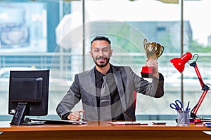 The businessman winning cup trophy in the office
