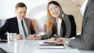 Businessman and woman with colleague sitting and working at meeting in sunny office