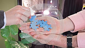 Businessman and woman hands exchanging puzzle pieces at business office