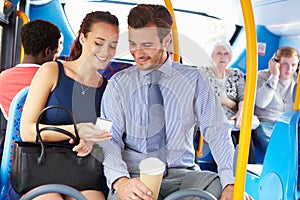 Businessman And Woman Looking At Mobile Phone On Bus