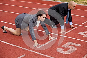 Businessman and woman on start line of running track