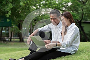 Businessman and woman use laptop in park with happy moment, sit