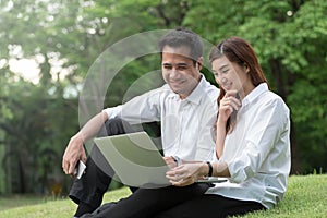 Businessman and woman use laptop in park with happy moment, sit