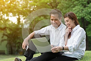 Businessman and woman use laptop in park with happy moment, sit