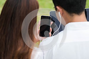 Businessman and woman use laptop and smartphone in park, sit on