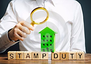 Businessman and wooden blocks with the word Stamp duty and house. Taxes assessed during the transfer of real estate between two