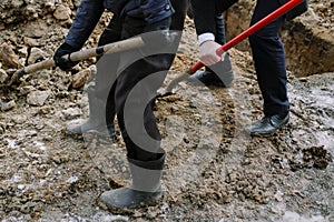 A businessman and a worker dig a hole, shovels the soil to cover the grave and bury the dead