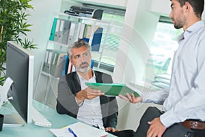Businessman and worker discussing over documents in office