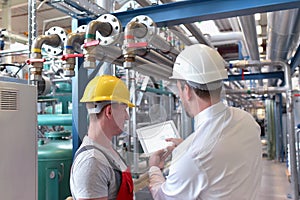 Businessman and worker meeting in a factory - maintenance and repair of the industrial plant
