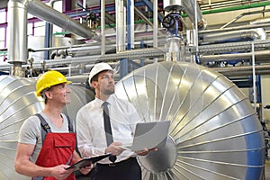 Businessman and worker meeting in a factory - maintenance and repair of the industrial plant
