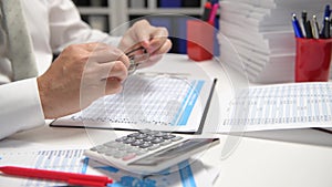 Businessman working and calculating, reads and writes reports. Office employee, table closeup. Business financial accounting conce