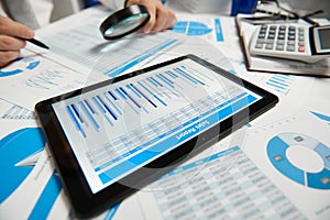 Businessman working and calculating, reads and writes reports. Using tablet pc. Office employee, table closeup. Business financial
