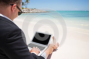 Businessman working with computer on the beach