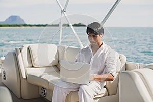 Businessman working with computer on a boat, nice outdoor office.