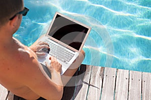 Businessman working with computer by the pool