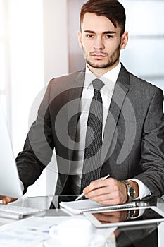 Businessman working with computer in sunny office. Headshot of male entrepreneur at workplace. Business concept