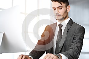 Businessman working with computer in sunny office. Headshot of male entrepreneur at workplace. Business concept