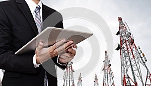 Businessman working on digital tablet, with satellite dish telecom network on telecommunication tower in the morning