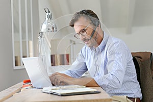 Businessman working with headset on laptop