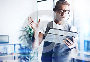 Businessman working on his digital tablet holding in hands. Elegant man wearing audio headset and making video