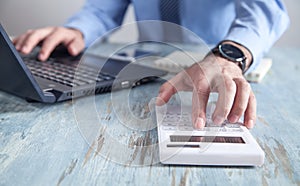 Businessman working on his laptop and using calculator