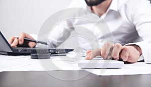 Businessman working on his laptop and using calculator