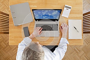 Businessman working from home with laptop, smartphone and calculator - view from above