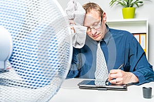 Businessman is working in a hot office and is sweating