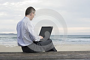 Businessman working with laptop on a beach