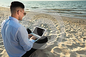 Businessman working with laptop on beach. Business trip