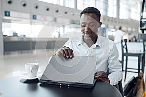 Businessman working on laptop in car showroom