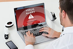 Businessman Using Laptop With Virus Alert On Screen