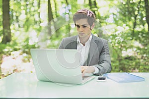 Businessman working on laptop computer in the forest at office table and smile at camera. Business concept.