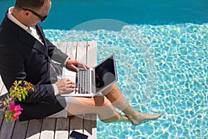 Businessman working with laptop computer by the pool