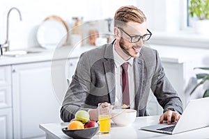 businessman working on laptop while eating breakfast photo