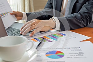 Businessman working on laptop with graph stock chart on table work from home concept.