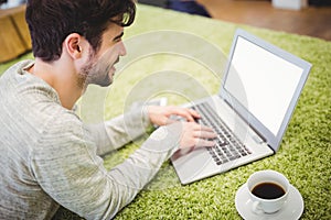 Businessman working on laptop while lying in office