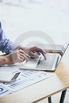 Businessman working laptop for new architectural project. Generic design notebook on the table. Blurred background, vertical mocku