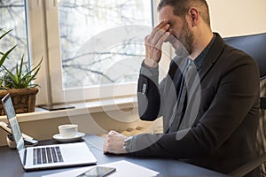 businessman working on laptop in office eyes hurt