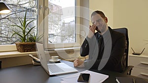 Businessman working on laptop in office eyes hurt