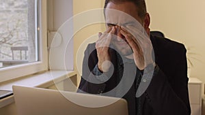 Businessman working on laptop in office eyes hurt