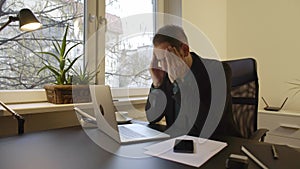 Businessman working on laptop in office eyes hurt