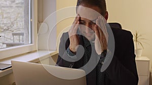 Businessman working on laptop in office headache