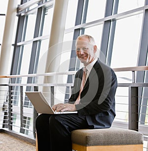 Businessman working on laptop in office lobby